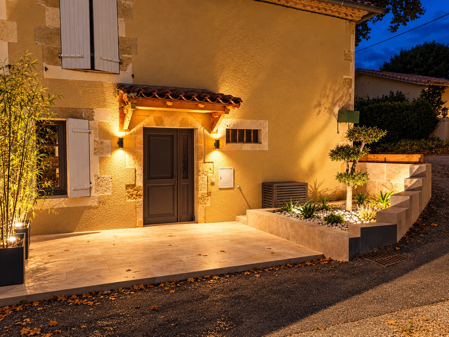 Après aménagement : terrasse en pierre, murets, plantations et éclairages de nuit