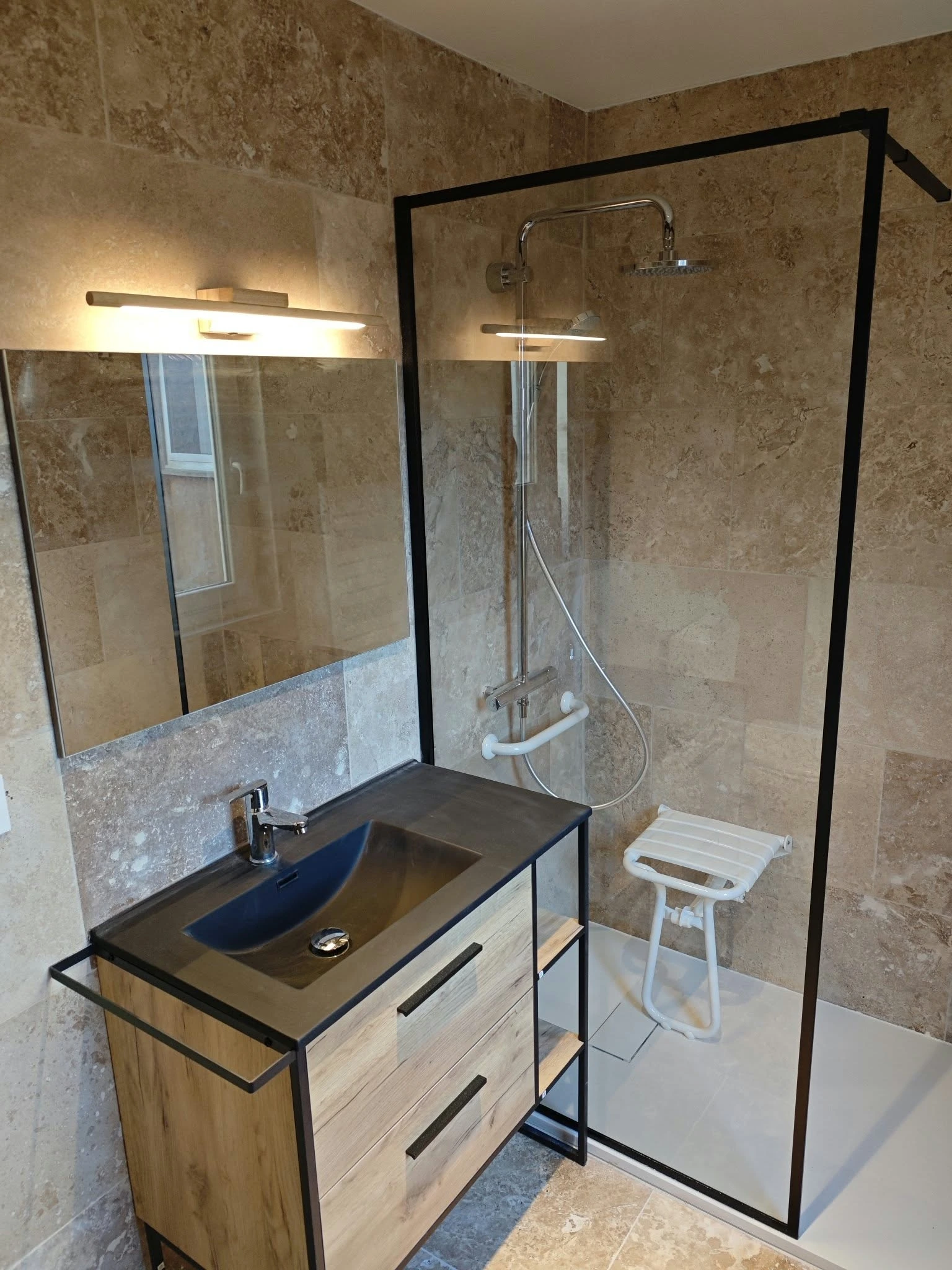 Salle de bains avec siège de douche et barre d’appui