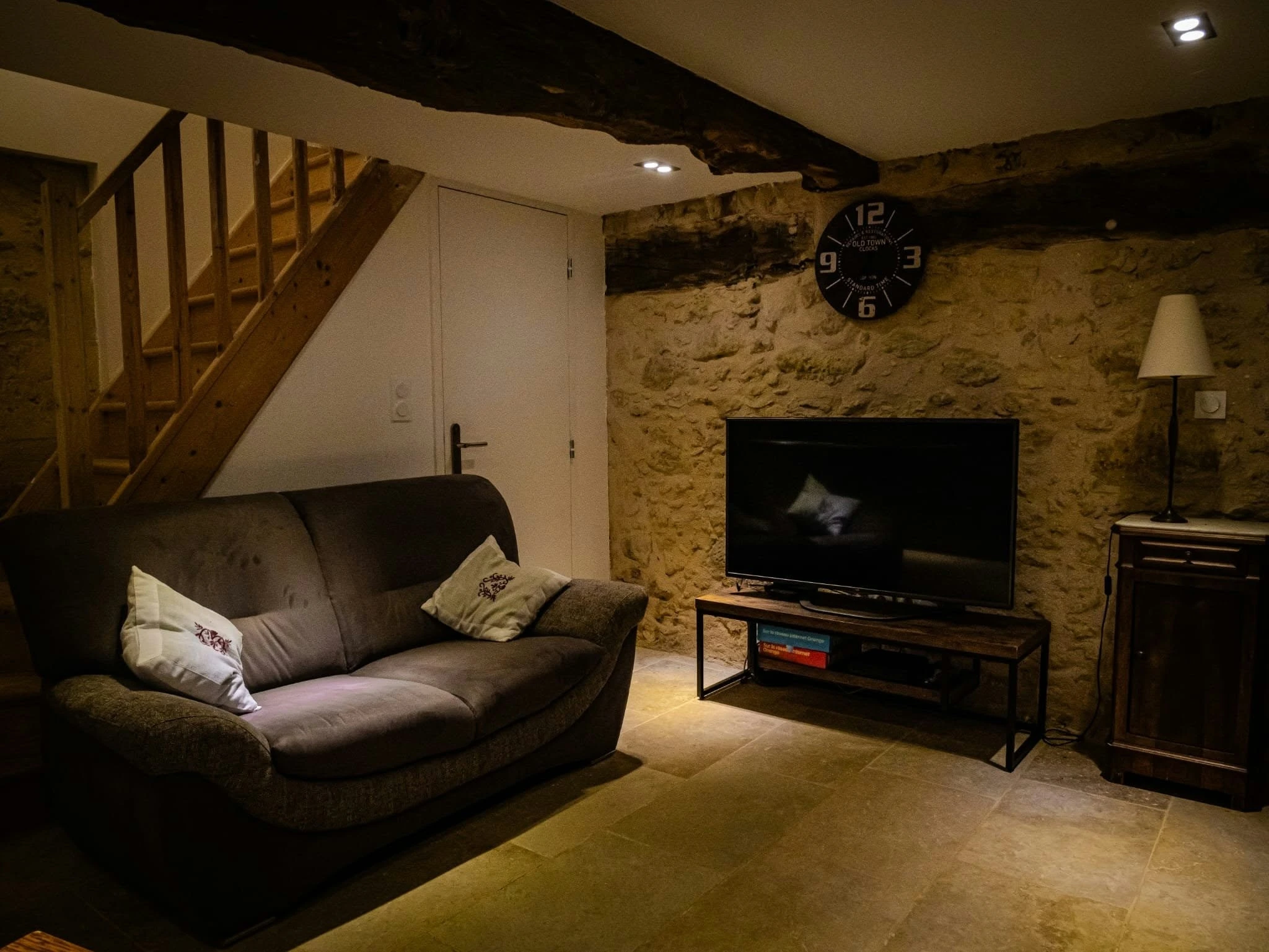 Salon rénové avec mur en pierre et poutres apparentes