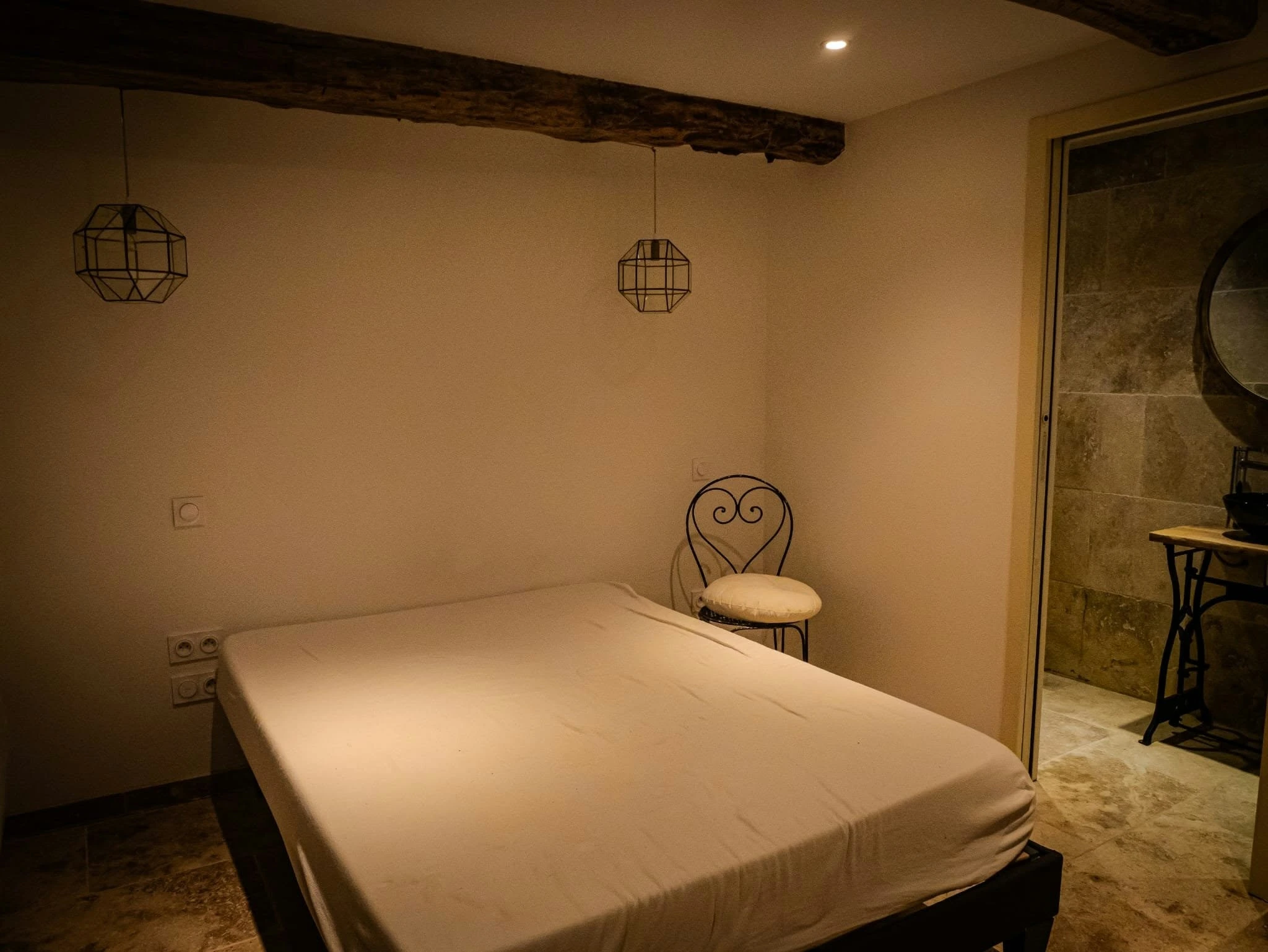 Chambre rénovée avec poutres apparentes et suspensions